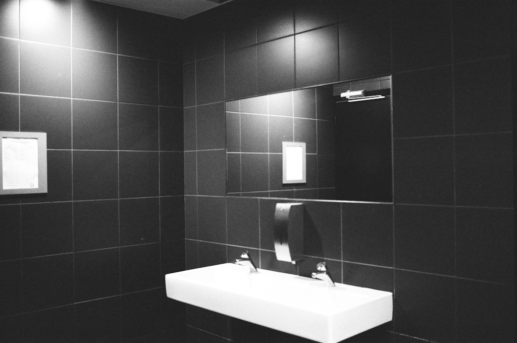 bathroom sink and mirror with black tiles