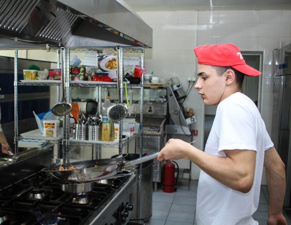 chef holding a pan over a stove