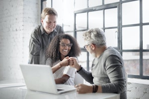 three employees having success and fist bumping