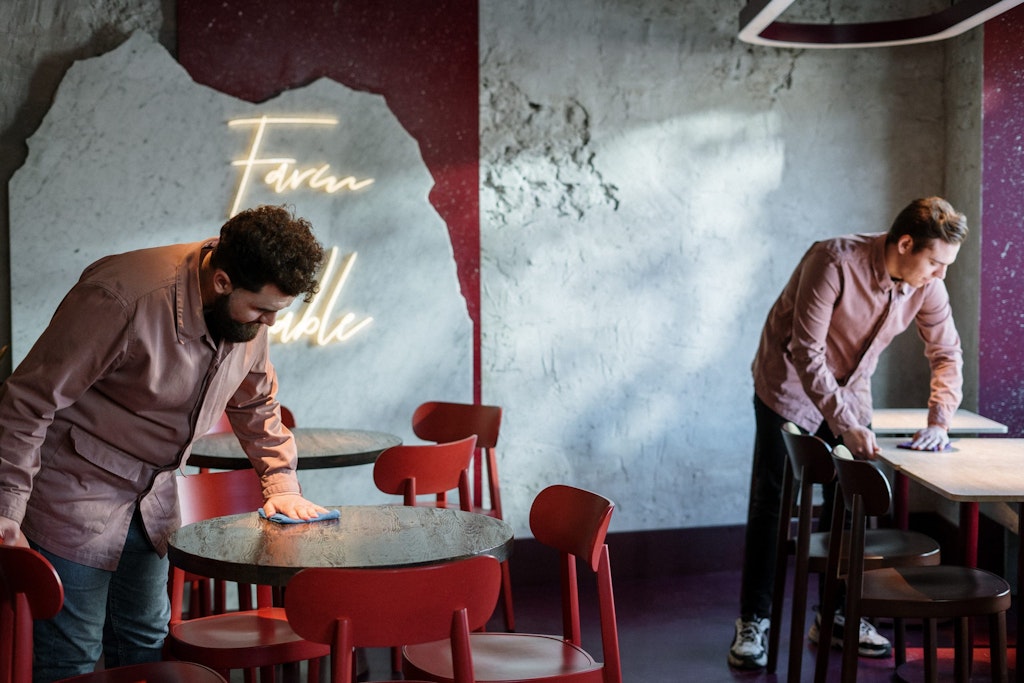 Two man cleaning round restaurant tables